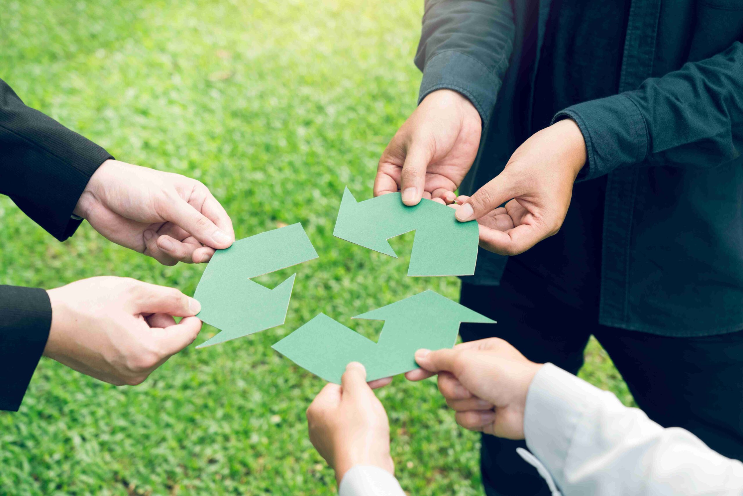 Teamwork assembling a recycle symbol outdoors